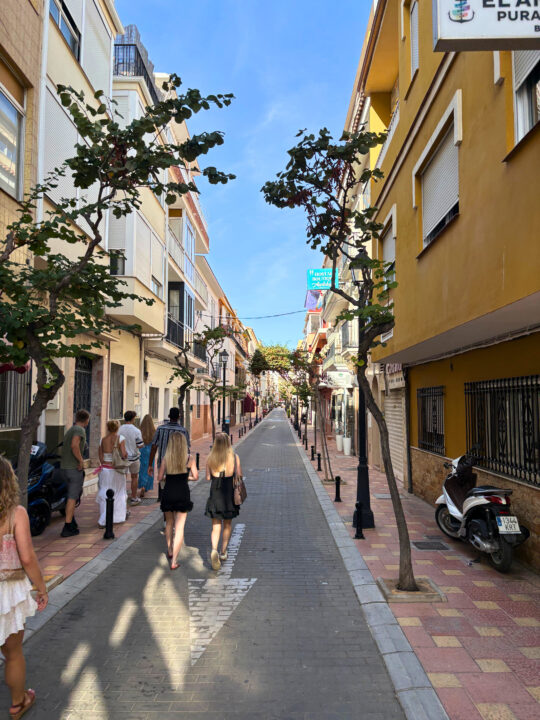 Studenter som går gjennom smal gate med leiligheter og butikker i sentrum av Fuengirola