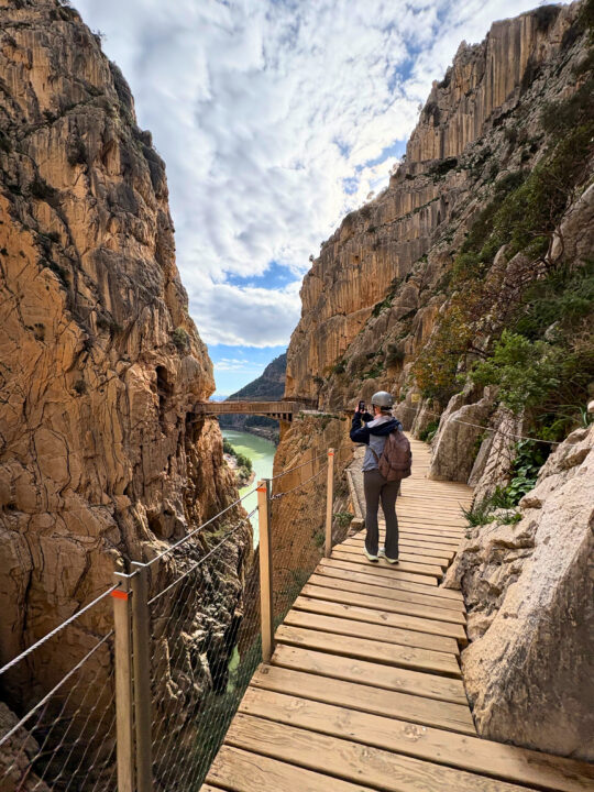 Student går på trebro gjennom dramatisk fjellandskap ved Caminito del Rey i Spania