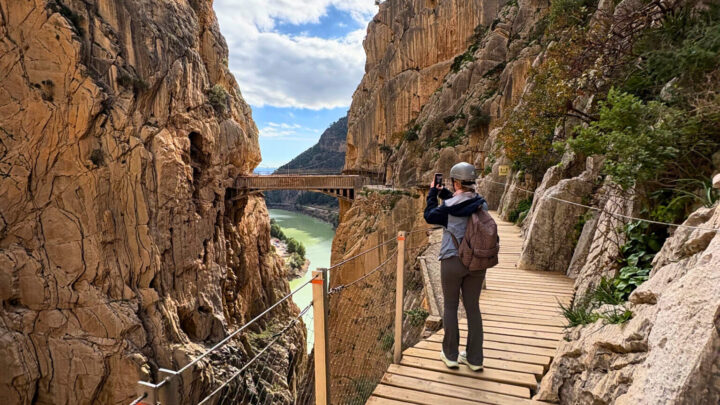 Student går på trebro gjennom dramatisk fjellandskap ved Caminito del Rey i Spania