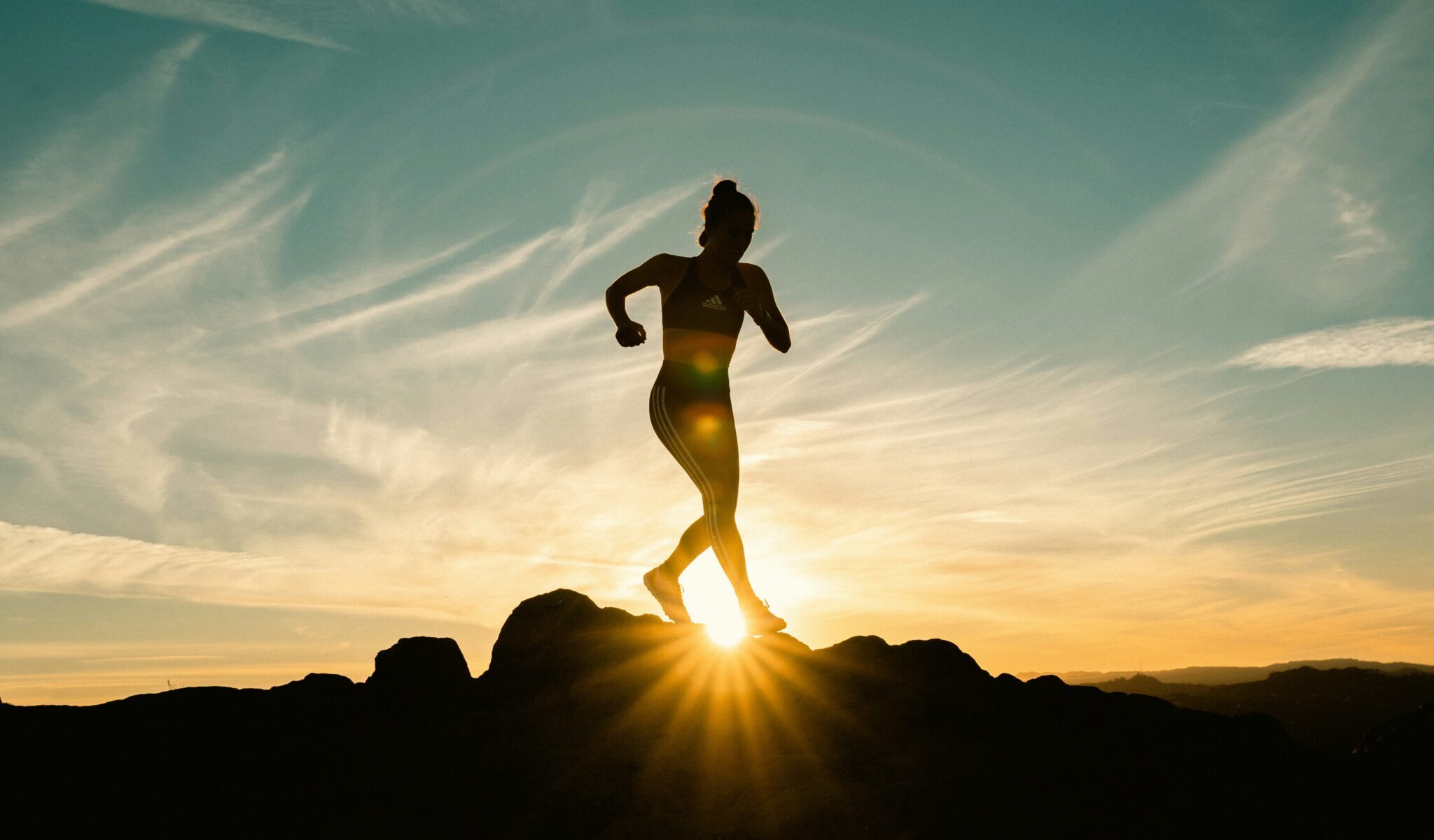 Kvinne som løper i fjellet ved solnedgang